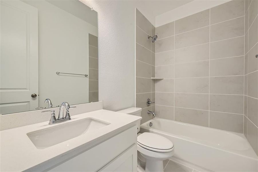 Full bathroom featuring tile floors, vanity, toilet, and tiled shower / bath combo