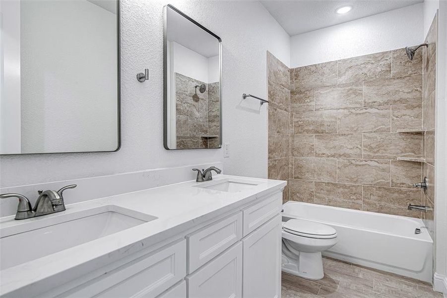 Full bathroom with wood finished floors, toilet, shower / tub combination, and double vanity Full bathroom with wood finished floors, toilet, shower / tub combination, and double vanity