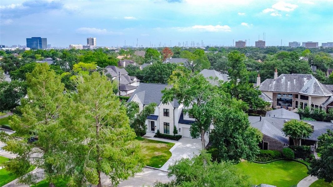 This aerial photo showcases the spacious, modern home nestled in the lush, green Afton Oaks neighborhood. The property is surrounded by mature trees, offering privacy and a serene atmosphere, yet being close to great restaurants, entertainment, and shopping. Minutes from Highland Village and the Galleria.