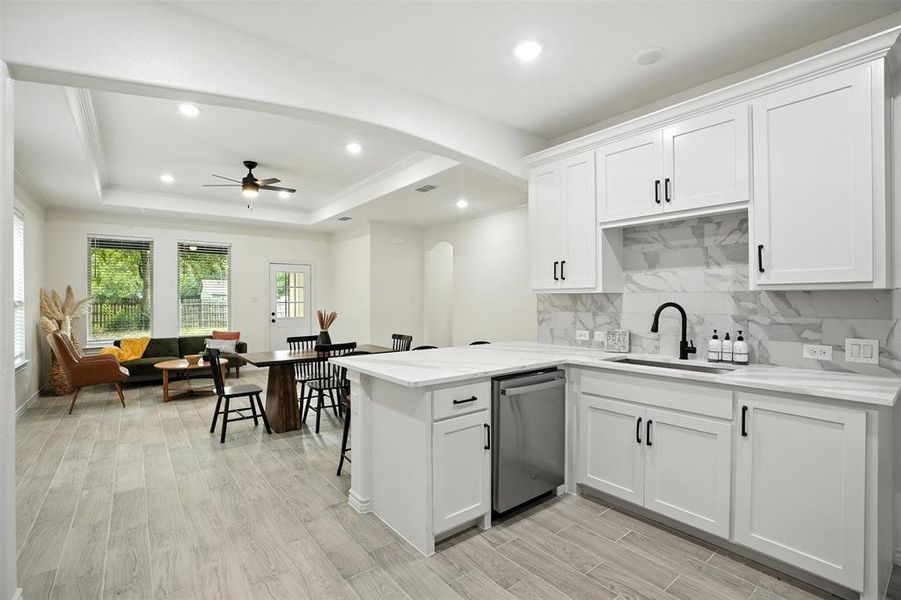 Kitchen featuring light wood-style floors, recessed lighting, ceiling fan, white cabinets, and arched walkways