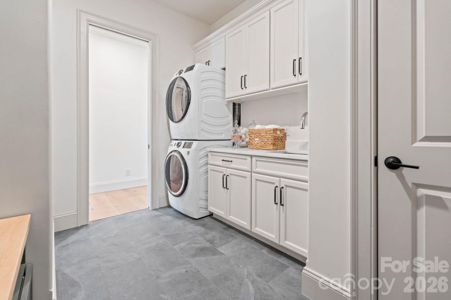 Laundry room includes drop-zone area, cabinets, sink and closet