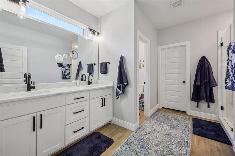 Full bathroom with a shower stall, double vanity, and light wood-style flooring Full bathroom with a shower stall, double vanity, and light wood-style flooring