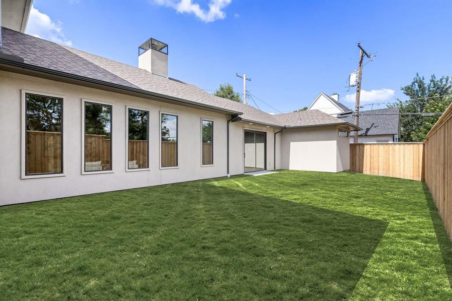 Rear view of property featuring a fenced backyard, a chimney, stucco siding, and a shingled roof Rear view of property featuring a fenced backyard, a chimney, stucco siding, and a shingled roof