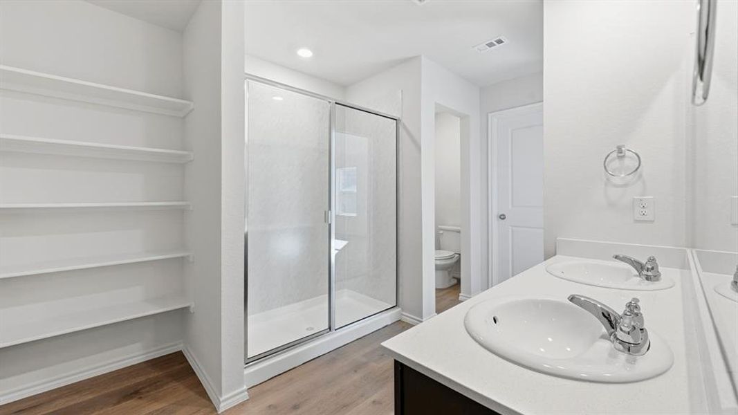 Full bath with light wood-type flooring, double vanity, a shower stall, recessed lighting, and a closet Full bath with light wood-type flooring, double vanity, a shower stall, recessed lighting, and a closet