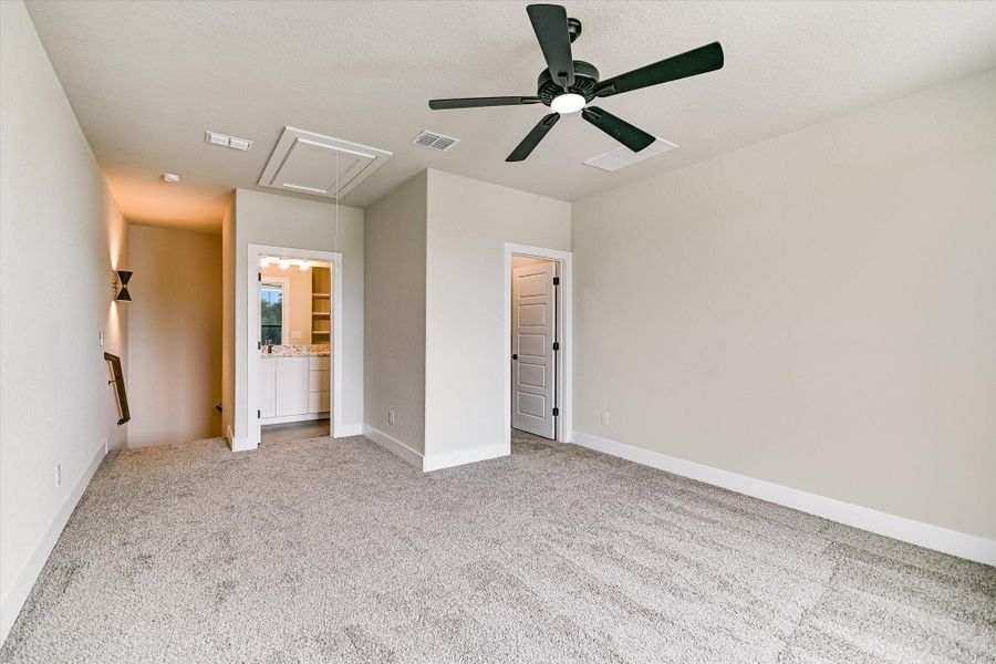 Unfurnished bedroom featuring light colored carpet, ceiling fan, and ensuite bath