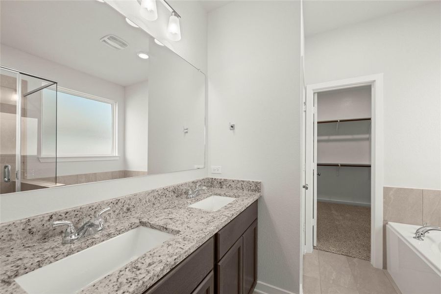 Double vanities with granite counters provide ample space in this well-appointed primary bathroom, offering a seamless blend of style and utility.