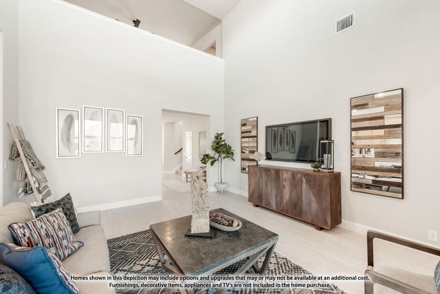 Living room with high ceilings, wood media console, wall-mounted TV, and neutral furnishings