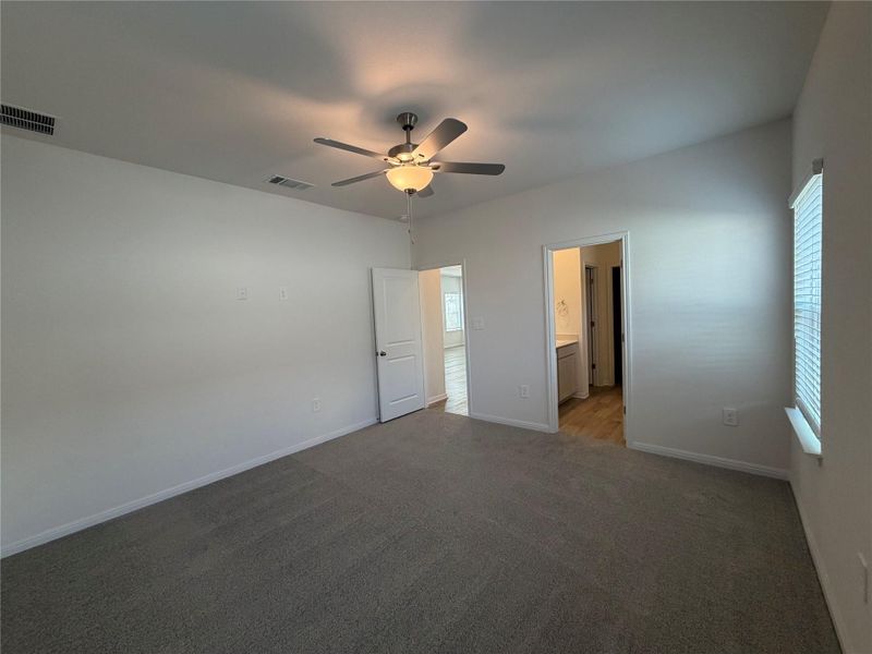 Unfurnished bedroom with carpet, a ceiling fan, and connected bathroom