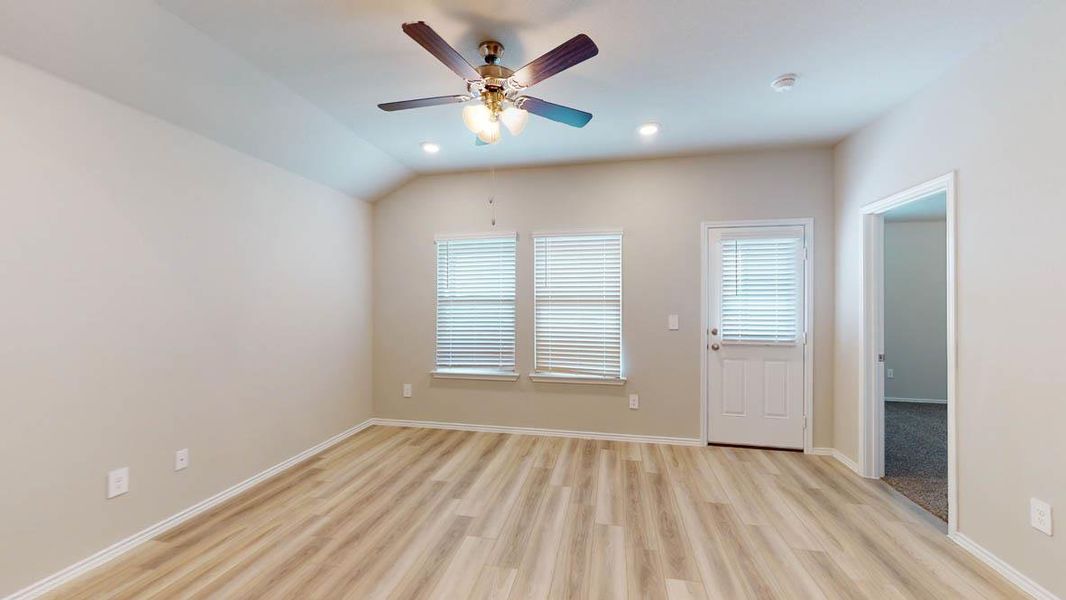 A living area with light wood-style flooring, a ceiling fan, and ample natural light through two windows. A living area with light wood-style flooring, a ceiling fan, and ample natural light through two windows.