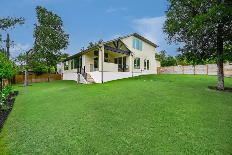 A vibrant green lawn embraces this contemporary residence with an inviting elevated patio and privacy fencing.