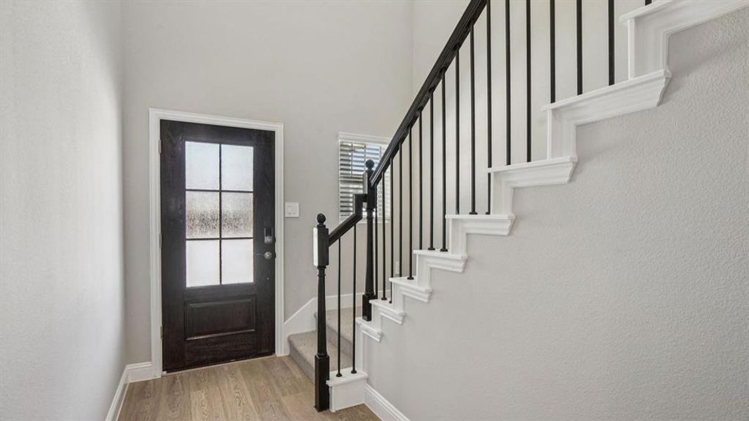 Foyer with stairs and light wood-style floors