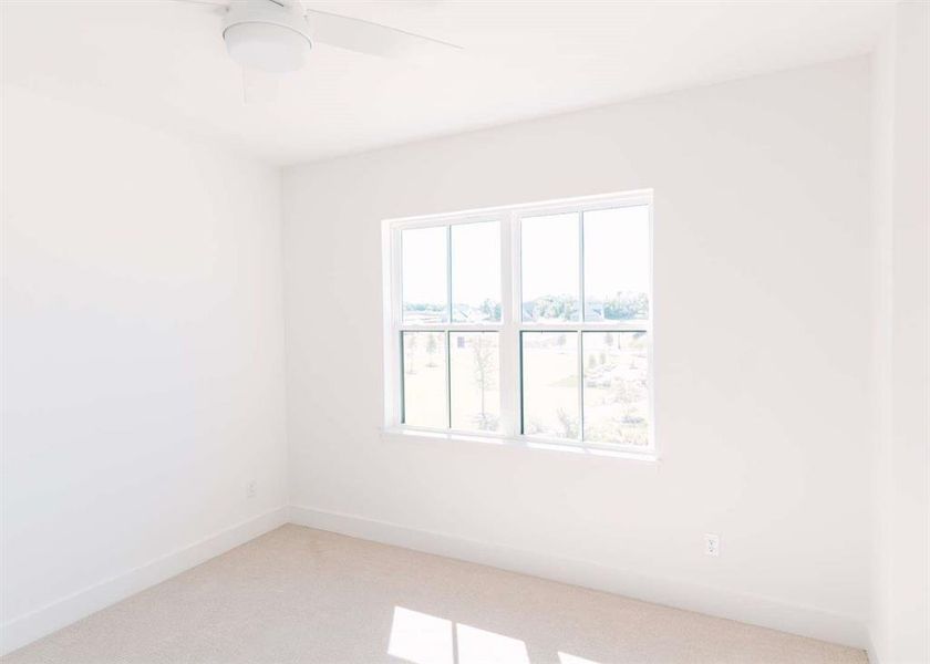 Carpeted spare room with ceiling fan and plenty of natural light