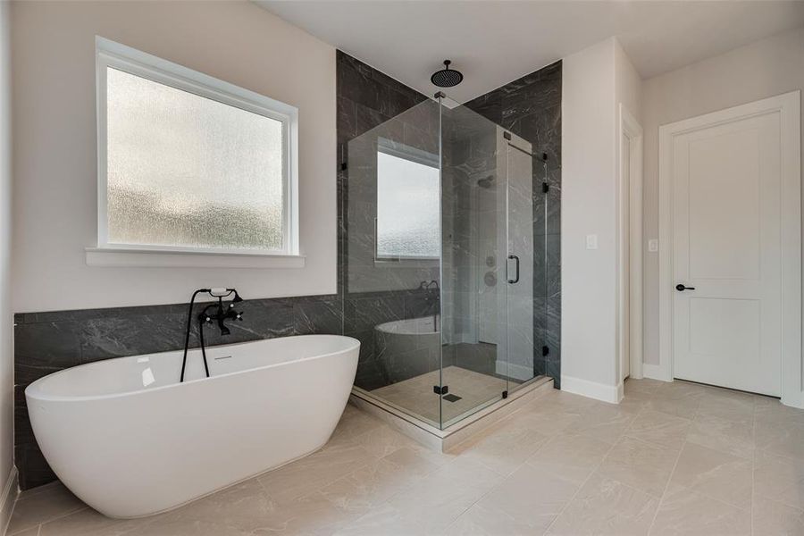 Full bathroom featuring a shower stall, a soaking tub, tile walls, and light tile patterned floors