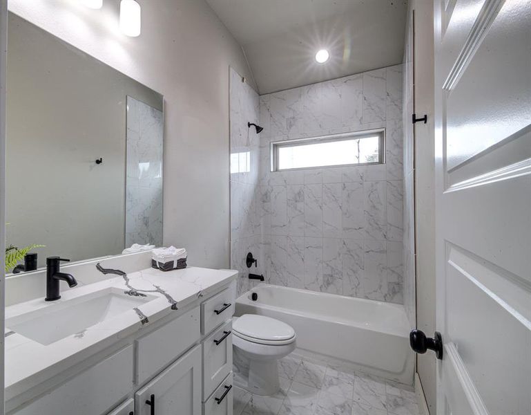 Full bathroom featuring tiled shower / bath combo, vanity, and toilet