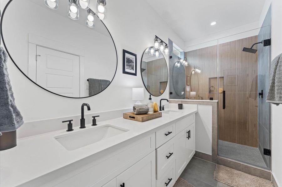 This luxurious primary bathroom blends modern elegance with spa-like comfort, featuring a spacious layout and contemporary selections throughout. A sleek double vanity with minimalist cabinetry and quartz countertops offers ample storage and style, while the glass-enclosed shower includes a built-in bench for added relaxation and convenience. This luxurious primary bathroom blends modern elegance with spa-like comfort, featuring a spacious layout and contemporary selections throughout. A sleek double vanity with minimalist cabinetry and quartz countertops offers ample storage and style, while the glass-enclosed shower includes a built-in bench for added relaxation and convenience.