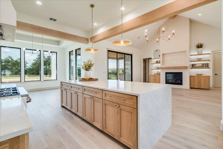 A grand, luminous kitchen island anchors this expansive open-concept living space with wide plank flooring.
