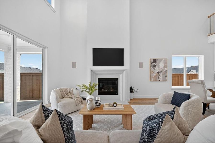 Living room featuring a towering ceiling, a glass covered fireplace, and wood finished floors Living room featuring a towering ceiling, a glass covered fireplace, and wood finished floors