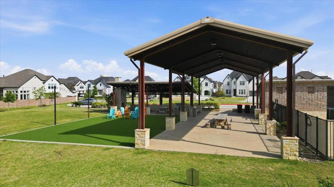 Expansive covered outdoor pavilion featuring stone-clad pillars, concrete flooring, and built-in picnic tables