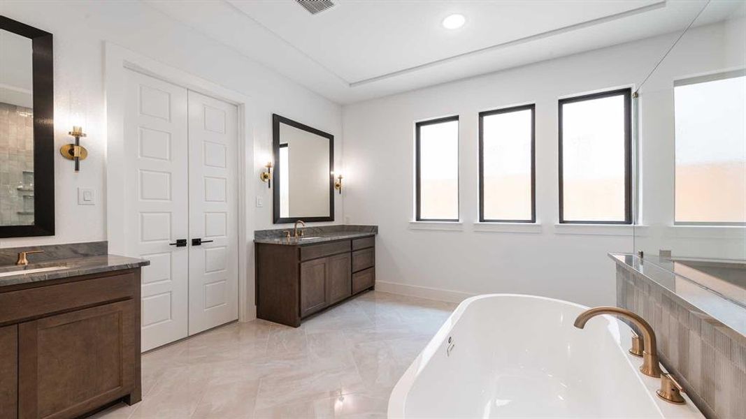 Full bath featuring a freestanding tub, two vanities, marble finish floors, and recessed lighting