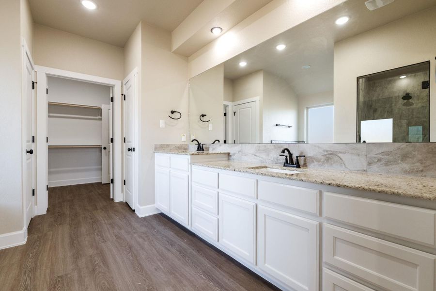 Bathroom with double vanity, dark wood finished floors, a spacious closet, a tile shower, and recessed lighting
