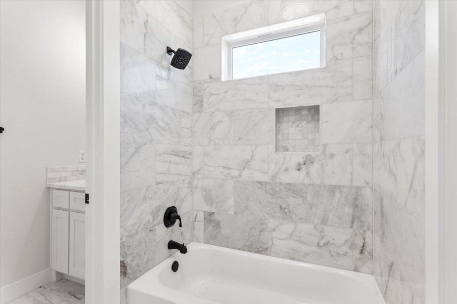 Bathroom with shower / bathtub combination, marble finish flooring, vanity, and baseboards Bathroom with shower / bathtub combination, marble finish flooring, vanity, and baseboards