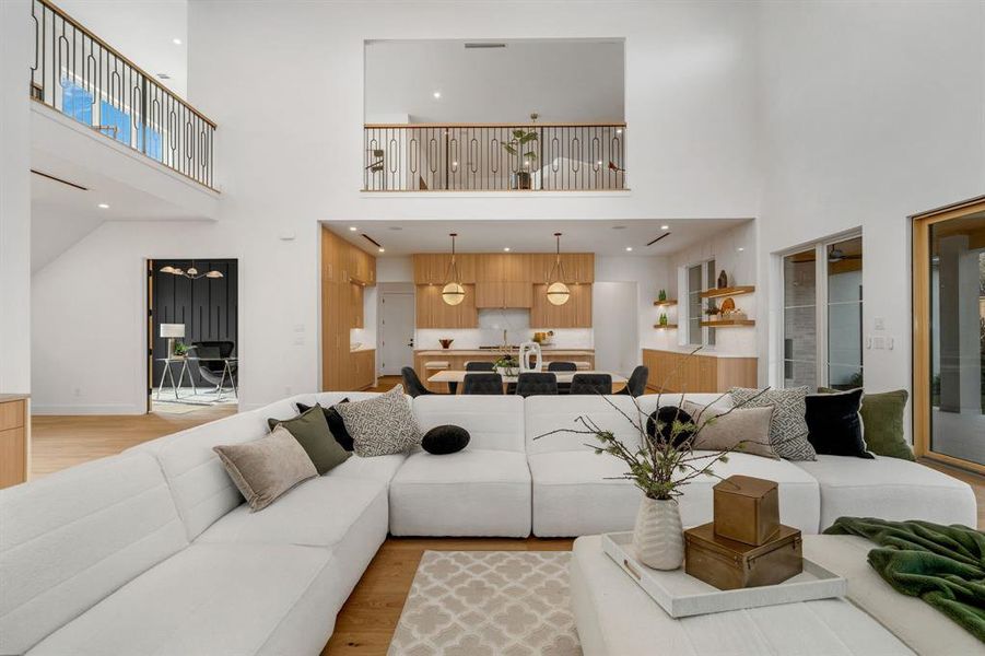 Living area with light wood-style floors, a high ceiling, and recessed lighting Living area with light wood-style floors, a high ceiling, and recessed lighting