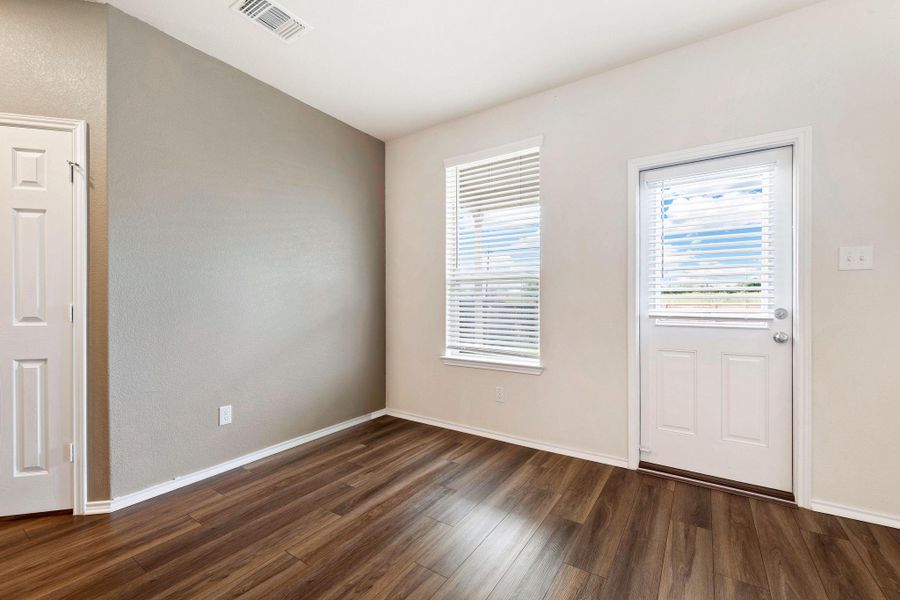 Rich hardwood-style flooring extends across this versatile interior space, illuminated by natural light from the exterior door. Rich hardwood-style flooring extends across this versatile interior space, illuminated by natural light from the exterior door.