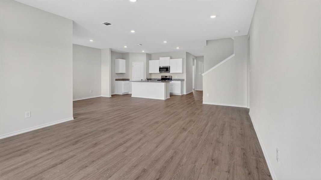 Open-concept living area with wood-finish flooring, recessed lighting, and a neutral color palette