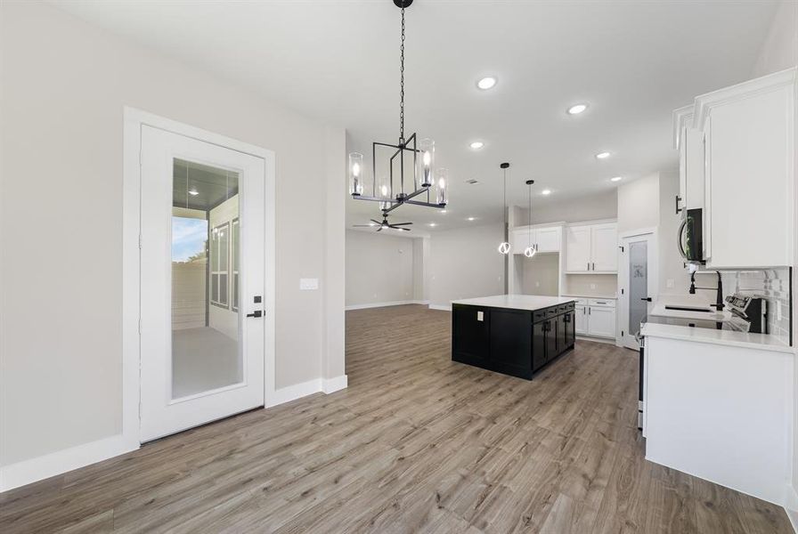 Kitchen with a chandelier, light countertops, white cabinetry, open floor plan, and recessed lighting Kitchen with a chandelier, light countertops, white cabinetry, open floor plan, and recessed lighting