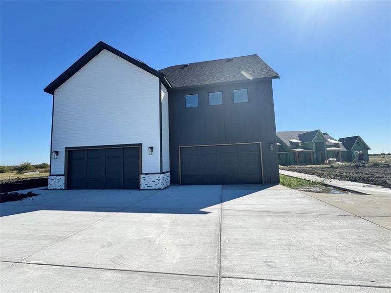 View of side of home with an attached garage and concrete driveway