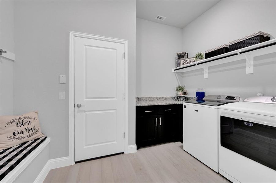 Separate laundry room with bench, hanging space and counter space