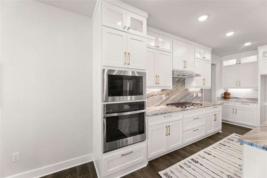 Kitchen with glass insert cabinets, backsplash, white cabinets, stainless steel appliances, and recessed lighting Kitchen with glass insert cabinets, backsplash, white cabinets, stainless steel appliances, and recessed lighting