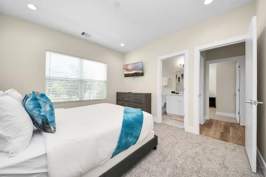A comfortable secondary bedroom with enough space for a full bedroom setup while maintaining easy access to the nearby bath.