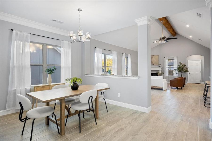 Dining room with ceiling fan with notable chandelier and vaulted ceiling with beams