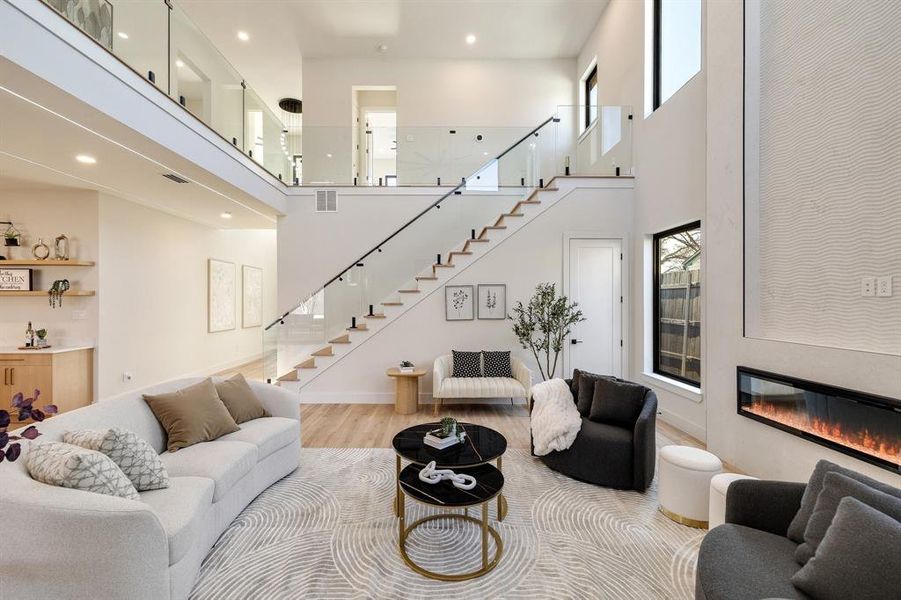 Living room featuring a high ceiling, plenty of natural light, and light wood-type flooring