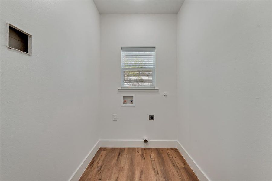 Laundry area featuring light wood-style floors, hookup for a washing machine, hookup for an electric dryer, and hookup for a gas dryer Laundry area featuring light wood-style floors, hookup for a washing machine, hookup for an electric dryer, and hookup for a gas dryer