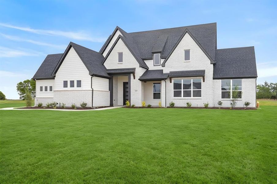 Modern farmhouse exterior featuring white brick and horizontal siding, dark shingle roof, dark trim accents, and a professionally landscaped front yard Modern farmhouse exterior featuring white brick and horizontal siding, dark shingle roof, dark trim accents, and a professionally landscaped front yard