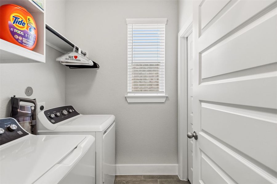Enjoy the convenience of a spacious laundry room with built-in shelving, natural light, and plenty of room for storage and organization.