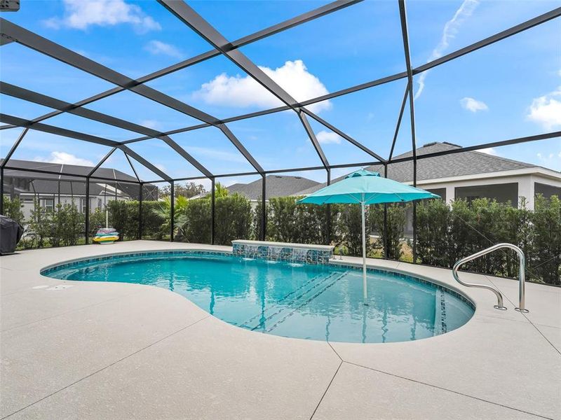 Pool area with expanded patio space, shallow shelf with umbrella, and three waterfalls