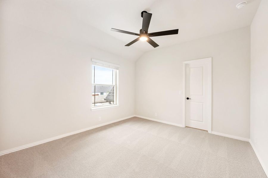 Empty bedroom with carpet flooring, vaulted ceiling, black ceiling fan, and single window