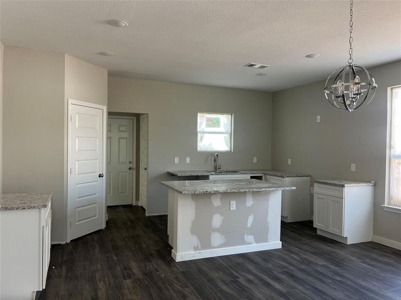 Kitchen featuring a center island, pendant lighting, dark hardwood / wood-style flooring, and white cabinetry