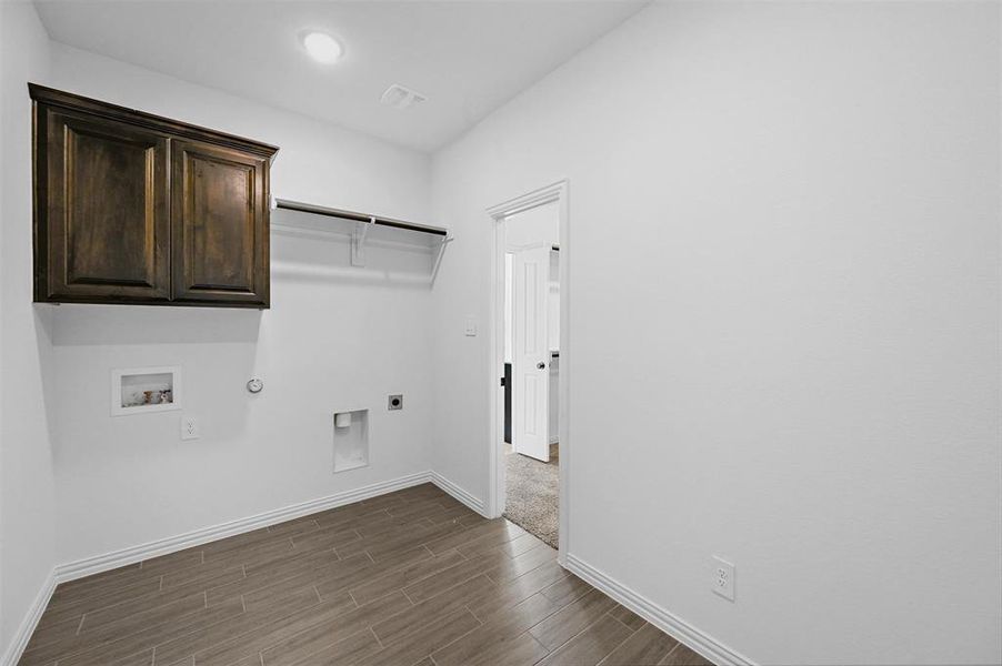 Clothes washing area with cabinets, washer hookup, dark hardwood / wood-style floors, electric dryer hookup, and hookup for a gas dryer