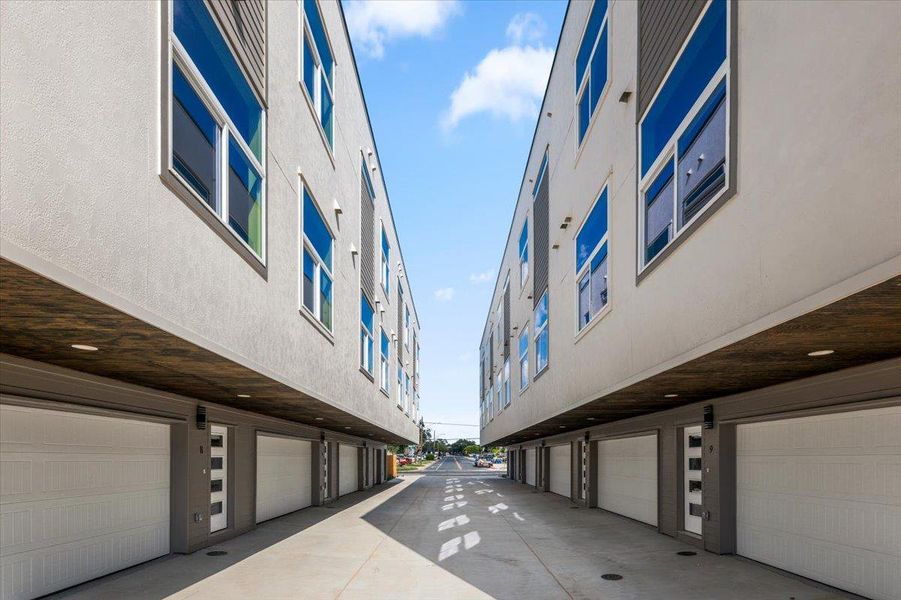 Modern townhomes line a concrete drive, each featuring integrated ground-level garages and ample window space.