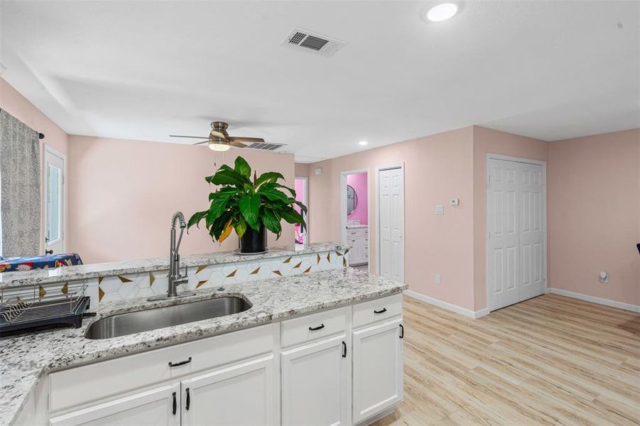 Kitchen featuring light stone counters, recessed lighting, white cabinets, light wood-style flooring, and a ceiling fan Kitchen featuring light stone counters, recessed lighting, white cabinets, light wood-style flooring, and a ceiling fan