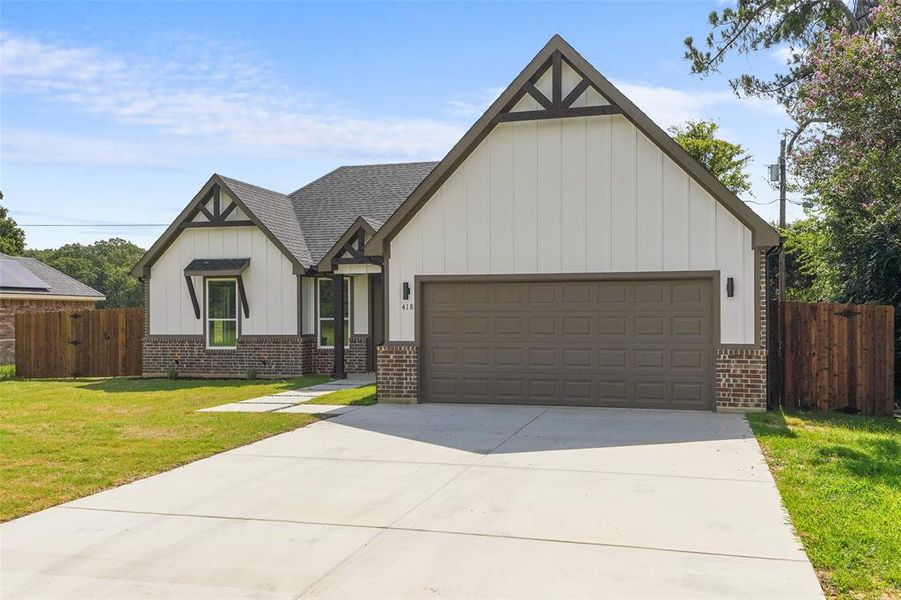Contemporary home exterior featuring board-and-batten siding, dark brick accents, a two-car garage, and a concrete driveway
