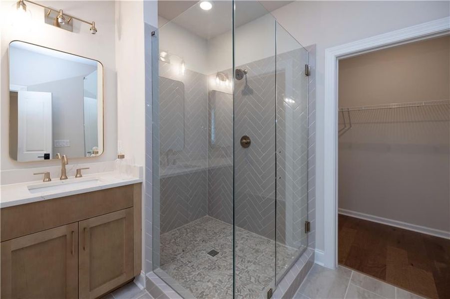 Bathroom with vanity, a shower stall, light tile patterned floors, and a walk in closet