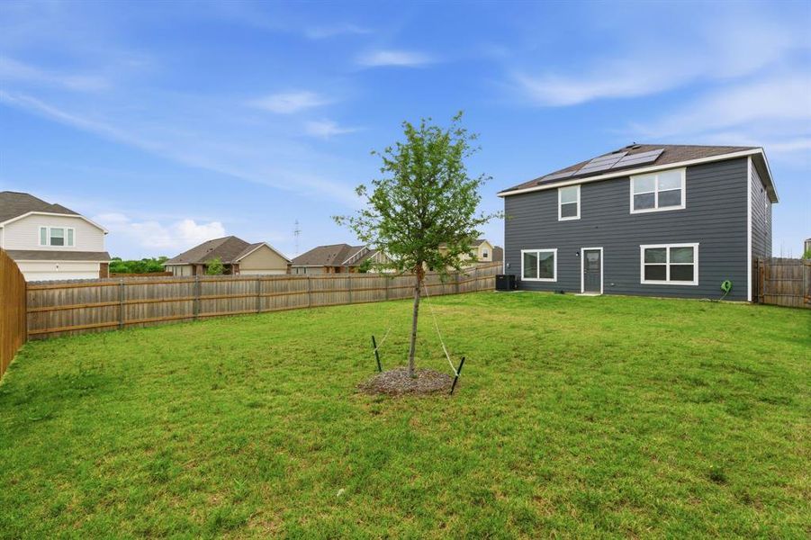 The property features a spacious rear yard with a well-maintained lawn and a privacy fence