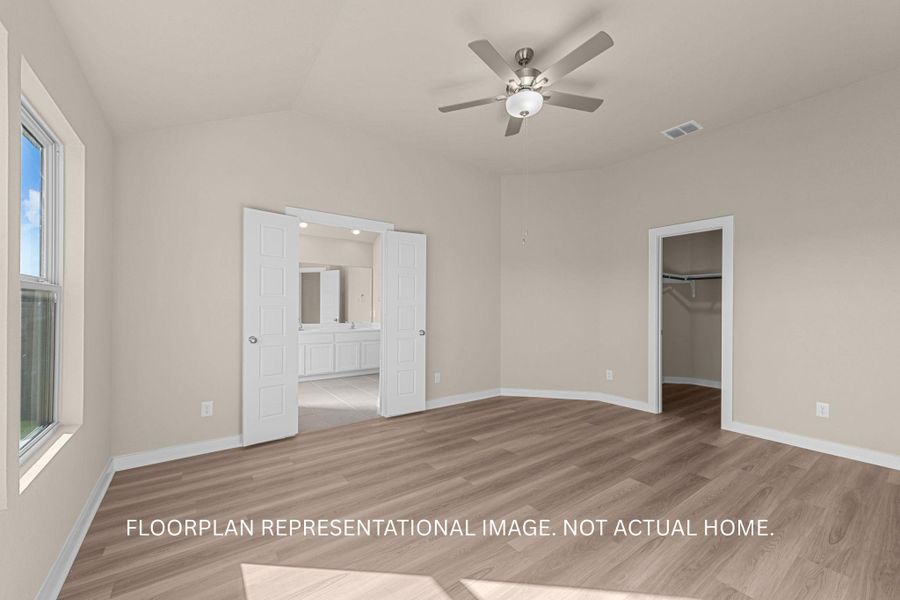An airy bedroom with a ceiling fan offers direct access to a well-appointed primary bathroom and a convenient walk-in closet.