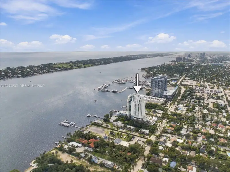 Aerial perspective of a high-rise tower situated on a coastal waterfront featuring direct proximity to a marina and expansive water scenery Aerial perspective of a high-rise tower situated on a coastal waterfront featuring direct proximity to a marina and expansive water scenery