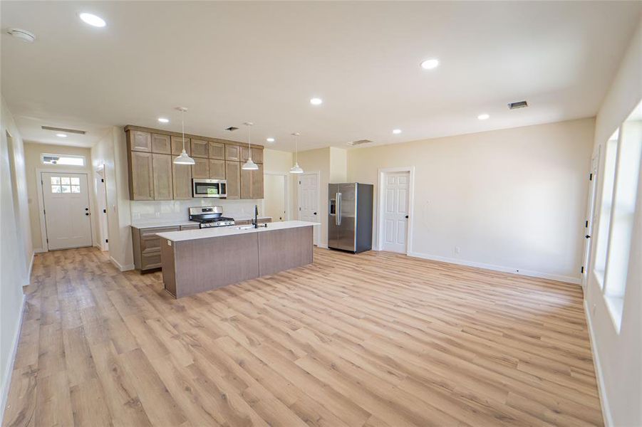 Open-concept living space featuring wood-finish flooring, recessed lighting, and multiple windows